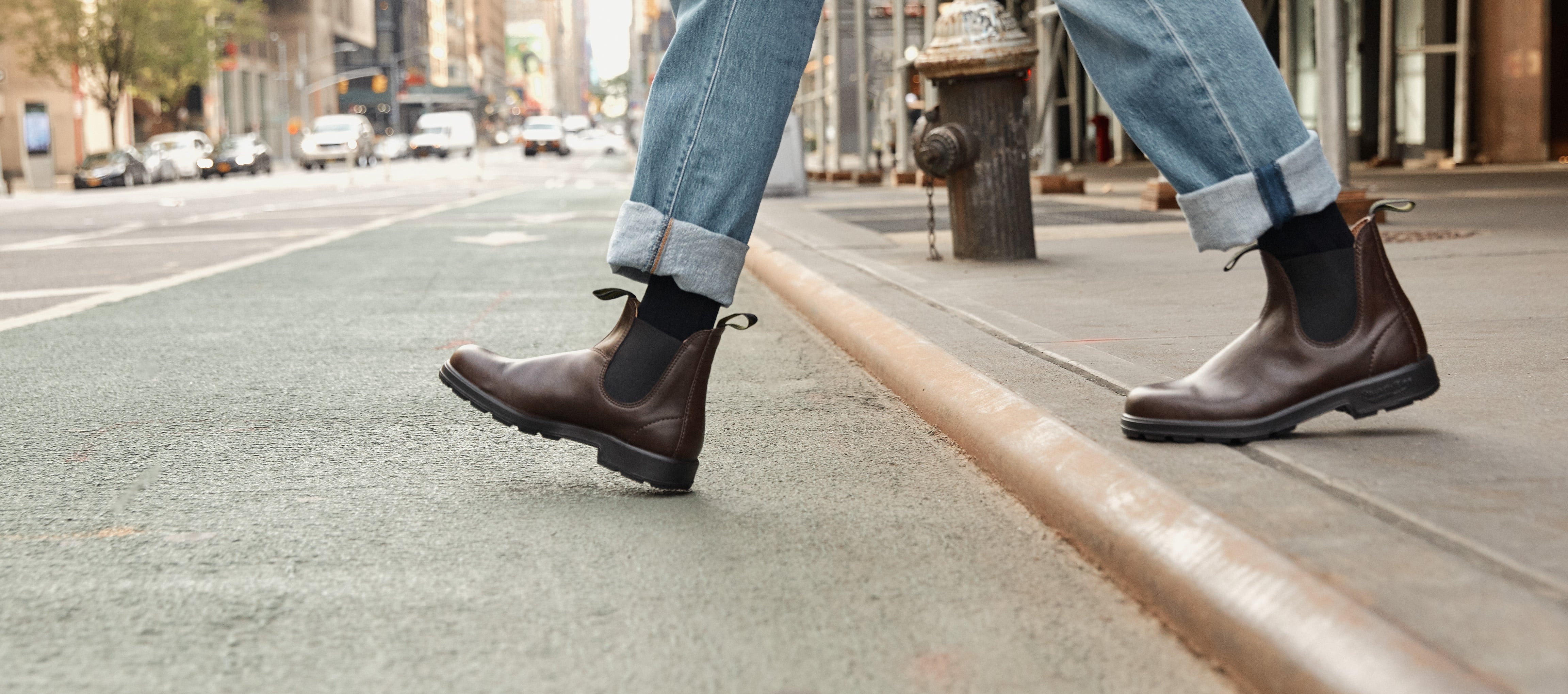 Black Friday Sale - Person wearing brown Blundstone boots and light blue jeans walking on a city street.