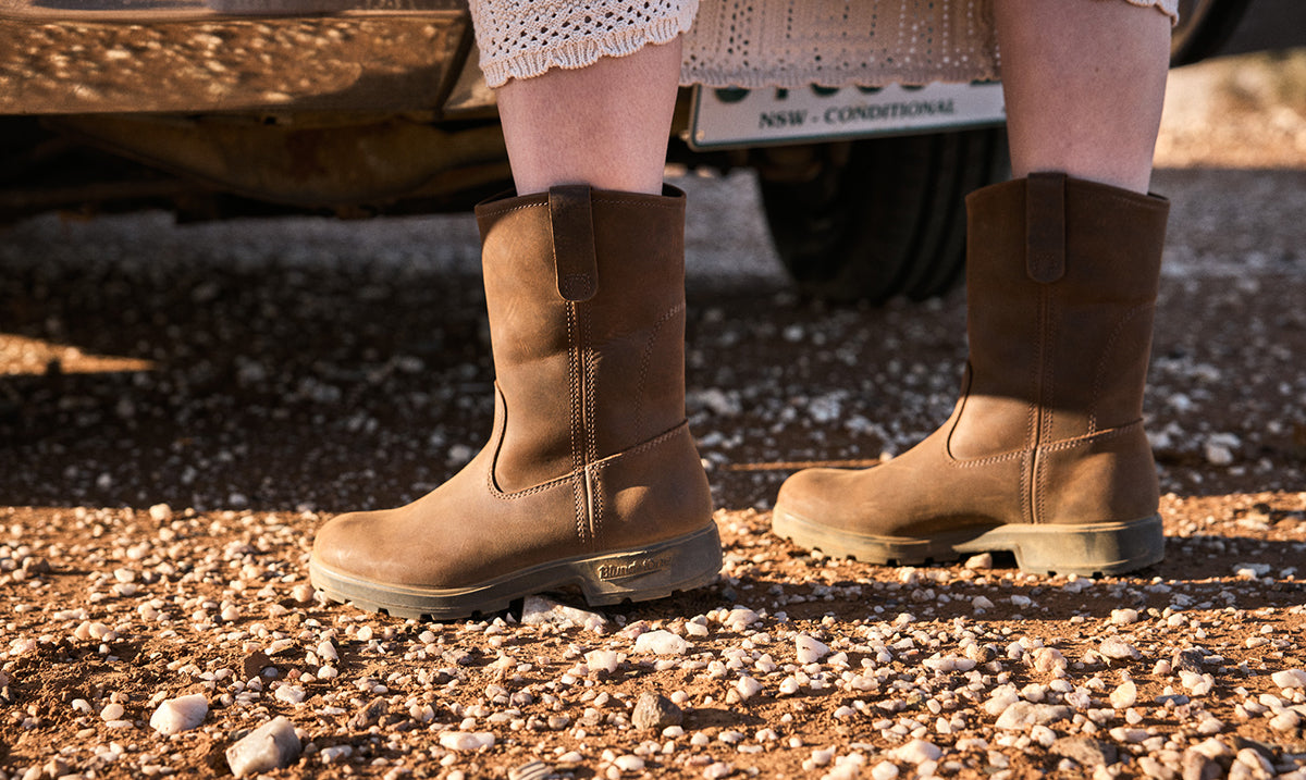 Brown boots on a gravel surface with a vehicle in the background