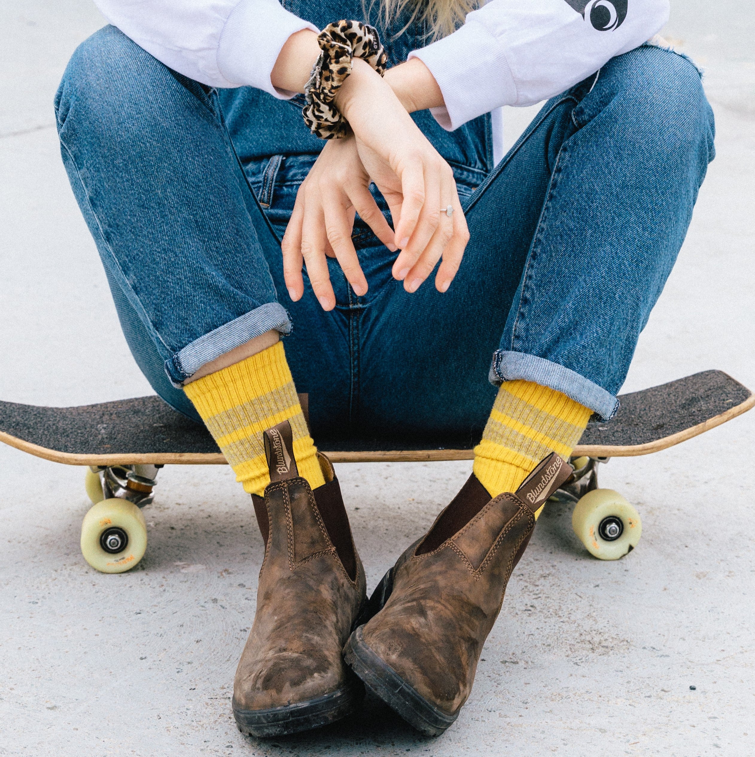 model sitting on skateboard wearing blundstone boots