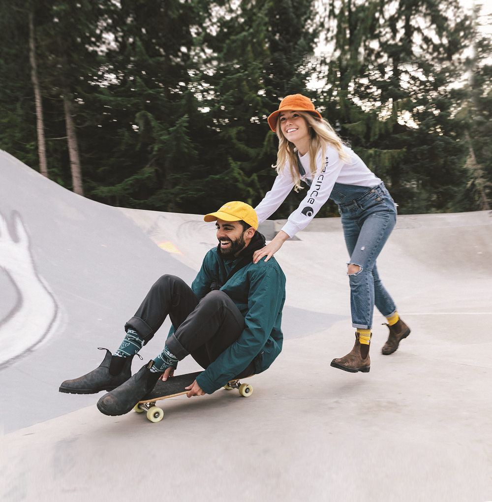 Girl pushing man on skateboard wearing blundstones